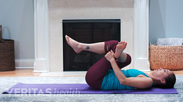 Woman laying on a mat performing a piriformis stretch.