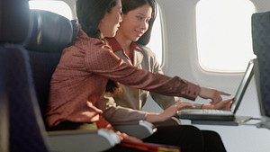 Two women talking while sitting in an airplane