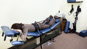 Woman lying prone on a spinal decompression chair