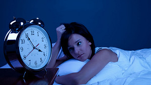 Woman staring at a clock in the middle of the night